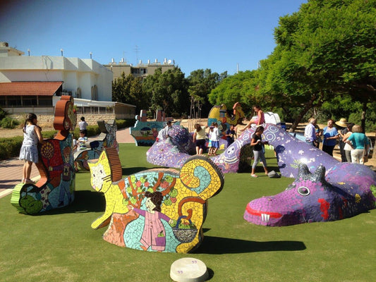 פסל סביבתי של מפלצת סגולה מעוצב בקונסטרוקציית מתכת ובטון עם ציפוי פסיפס צבעוני, יצירתו של חן וינקלר בחולון